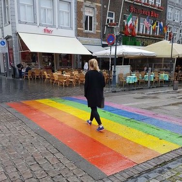 A woman crossing a rainbow-styled pedestrian crossing
